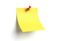 Yellow sticky note with red thumbtack pinned on a white surface Royalty Free Stock Photo