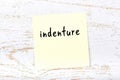 Yellow sticky note on wooden wall with handwritten word indenture Royalty Free Stock Photo