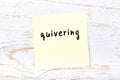 Yellow sticky note on wooden wall with handwritten word quivering
