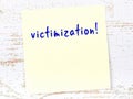 Yellow sticky note on wooden wall with handwritten word victimization Royalty Free Stock Photo