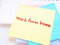 Yellow sticky paper Write a handwritten message `work from home` on monthly notebook.