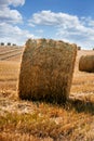 Straw bale of hay in the stubble field under a blue sky with clouds Royalty Free Stock Photo