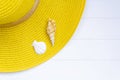 Yellow straw hat and shells on white wooden table. Top view with copy space Royalty Free Stock Photo