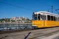 A yellow streetcar in downtown Budapest, with Buda Castle in background