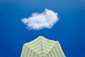 Yellow striped parasol against bright blue sky with one cloud