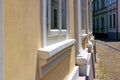 Renovated old yellow stucco house elevation closeup with new wood windows, sills and columns. Stone footing and cobble pavement