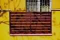 yellow stucco street fence closeup with brown horizontal metal lattice infill panels. Royalty Free Stock Photo