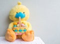 Yellow stuffed toy duck wearing a blue face mask and holding an Easter basket filled with Easter eggs