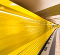 Yellow subway train speeding up on a city station. Business and Royalty Free Stock Photo