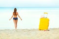 Yellow suitcase on the beach and a girl walks into the sea in th Royalty Free Stock Photo