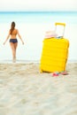 Yellow suitcase on the beach and a girl walks into the sea in th Royalty Free Stock Photo