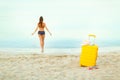 Yellow suitcase on the beach and a girl walks into the sea in th Royalty Free Stock Photo