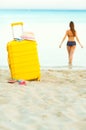Yellow suitcase on the beach and a girl walks into the sea in th Royalty Free Stock Photo