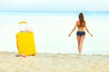 Yellow suitcase on the beach and a girl walks into the sea in th Royalty Free Stock Photo