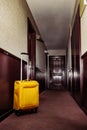 Yellow suitcase stand in hall of a hotel corridor