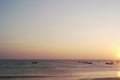 Setting half sun just above the horizon in the side middle of the frame, silhouettes of the boats in the foreground.