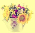 Yellow sunflowers and colored wild flowers in a white sprinkler, close up