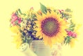 Yellow sunflowers and colored wild flowers in a white sprinkler, close up