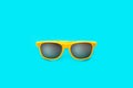 Yellow sunglasses in intense cyan blue large background. Minimal image concept for ready for summer