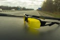 Yellow sunglasses lying on the dashboard passenger car that moving on Ukrainian high-way