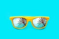 Yellow sunglasses with palm tree reflections in intense cyan blue background. Minimal image concept for ready for summer Royalty Free Stock Photo