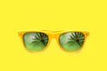 Yellow sunglasses summer concept with palm tree reflections isolated in yellow background. Royalty Free Stock Photo