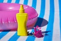 Yellow sunscreen cream bottle for skin protection on striped mattress and inflatable ring and blooming bougainvillea. Royalty Free Stock Photo