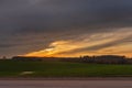 Yellow sunset in dramatic sky over the green fields and countryside road Royalty Free Stock Photo