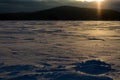 Yellow sunset on the frozen and snow-covered lake. Snow dust Royalty Free Stock Photo