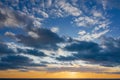 Yellow sunset and puffy clouds in the sky pierced with sun rays. Beautiful nature background Royalty Free Stock Photo