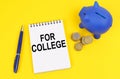 On a yellow surface, a piggy bank, coins and a notepad with the inscription - For college