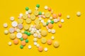 On the yellow surface scattered multi-colored tablets, concept medicine and allergy Royalty Free Stock Photo