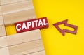 On a yellow surface are wooden blocks and an arrow pointing to a block with the inscription - Capital Royalty Free Stock Photo