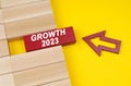On a yellow surface are wooden blocks and an arrow pointing to a block with the inscription - growth 2023 Royalty Free Stock Photo