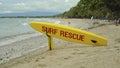 Yellow surfboard on beach with red text surf rescue emergency on a beach