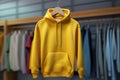 Yellow sweatshirt with hood and pocket hanging on a hanger