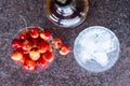 Yellow sweet cherries in a whiskey glass, ice cubes and a bottle of whiskey against a stone background. A refreshing cold cocktail Royalty Free Stock Photo