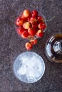 Yellow sweet cherries in a whiskey glass, ice cubes and a bottle of whiskey against a stone background. A refreshing cold cocktail Royalty Free Stock Photo