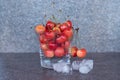 Yellow sweet cherries in a whiskey glass, ice cubes and a bottle of whiskey against a stone background. A refreshing cold cocktail Royalty Free Stock Photo