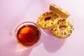 Yellow sweets - donuts biscuits and black tea in glass cup on pink table with sunshine, top view Royalty Free Stock Photo