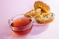 Yellow sweets food - donuts biscuits and tea in cup on pink table with sunshine Royalty Free Stock Photo