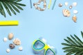 yellow swimming mask and snorkel, shells, palm leaves, drinking straws, shell bracelet on blue background Flat lay Top Royalty Free Stock Photo
