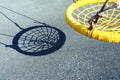 Yellow swing in the form of a web and a shadow from it. Minimalism.