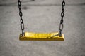 An empty yellow swing on metal chain