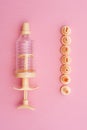 Yellow syringe for applying glaze on confectionery products on pink