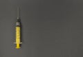 Yellow syringe on grey background. Simple flat lay with copy space