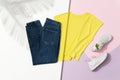 Yellow t-shirt, blue jeans and white sneakers on pink and white background Royalty Free Stock Photo