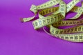 Yellow tailor measuring tape on a lilac background