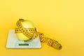 Yellow tape-line and apple on the digital kitchen scale on a yellow background. Concept of overeating, excess weight and obesity. Royalty Free Stock Photo