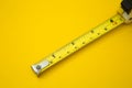 Yellow tape measure on yellow background and copy space